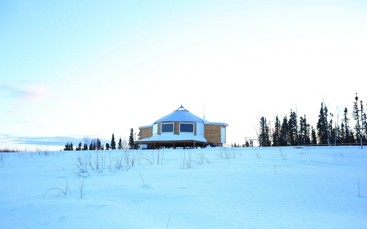 A blue yurt standing in deep snow at a sled dog kennel near Fairbanks